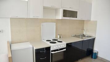 Una cocina compacta equipada con refrigerador, estufa, horno, microondas, pileta y alacenas.