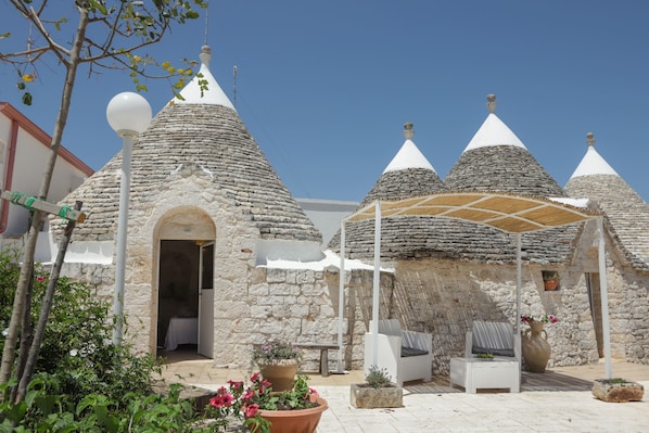 Un bâtiment en pierre doté de toits coniques, d’un espace de repos couvert et d’une porte d’entrée donnant sur un espace intérieur.