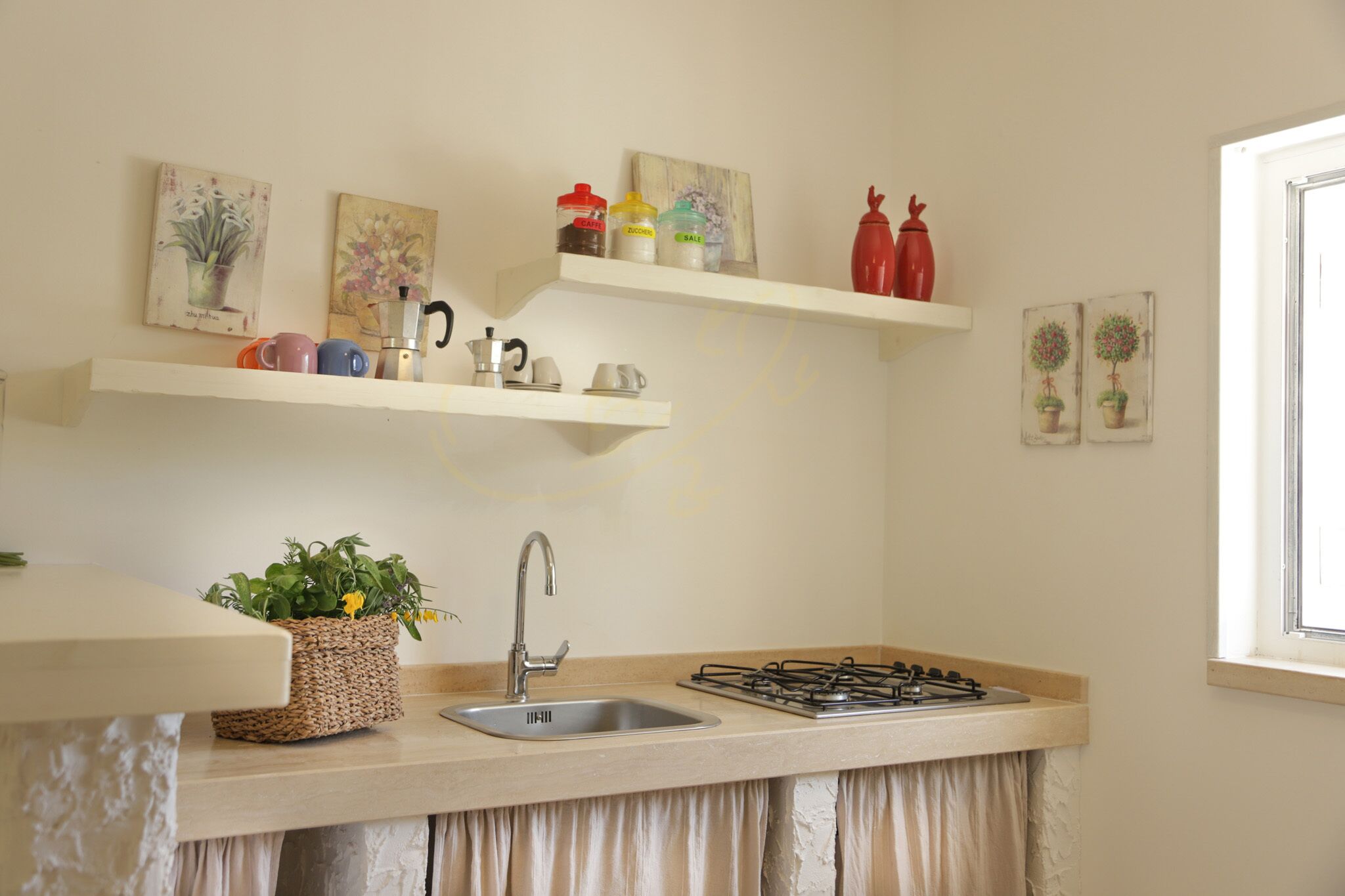 A kitchen with a sink, stove, and shelves with kitchenware and decorative items.