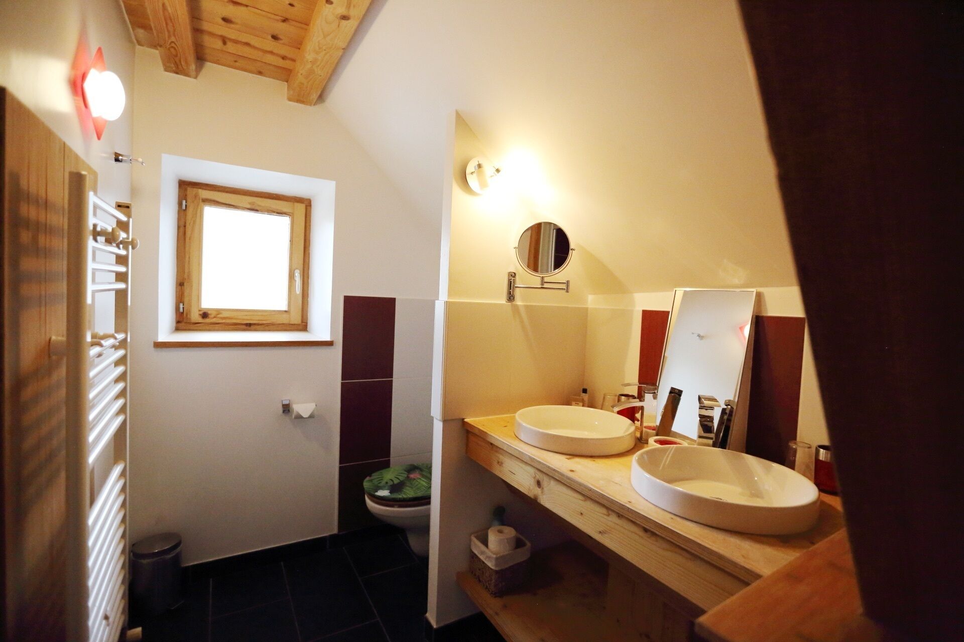 A bathroom with two sinks, a window, a toilet, and a towel rack.