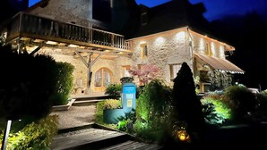 A stone building with a balcony, a sign indicating it is a hotel, and well-maintained gardens. - Le ValOmbre (Saint-Pierre-de-Chartreuse)