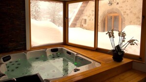 A hot tub with a view of a snowy landscape through large windows. - Le ValOmbre (Saint-Pierre-de-Chartreuse)