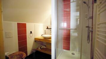 Une salle de bain comprenant des toilettes, un lavabo et un espace douche.