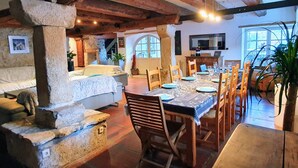 A rustic dining area with a long table set for six, wooden chairs, and a stone pillar. - Le ValOmbre (Saint-Pierre-de-Chartreuse)