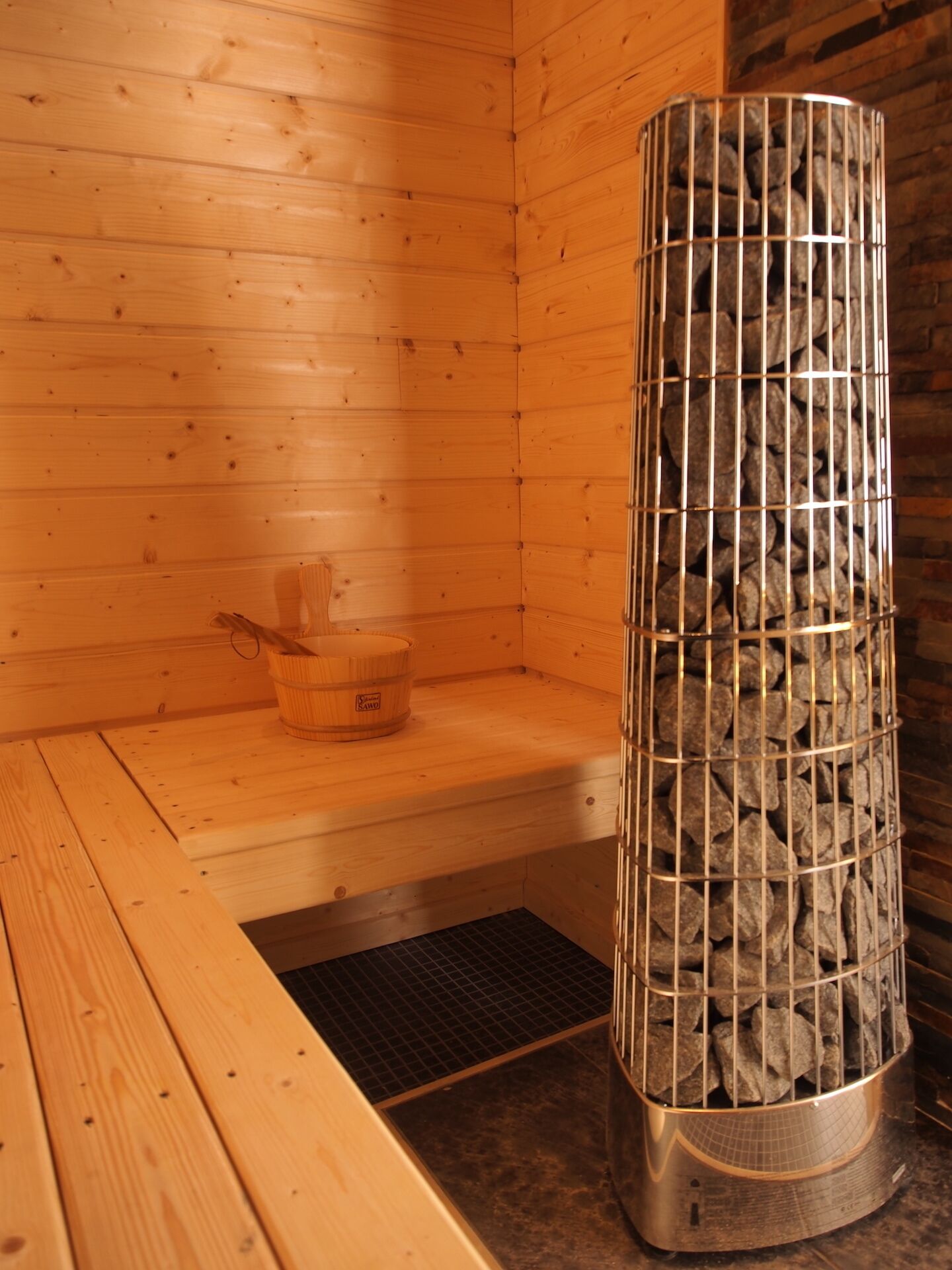 Un sauna aux murs en bois et un récipient en métal rempli de pierres.