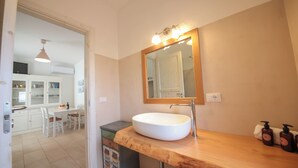Un baño con tocador de madera, lavamanos blanco y espejo con iluminación.