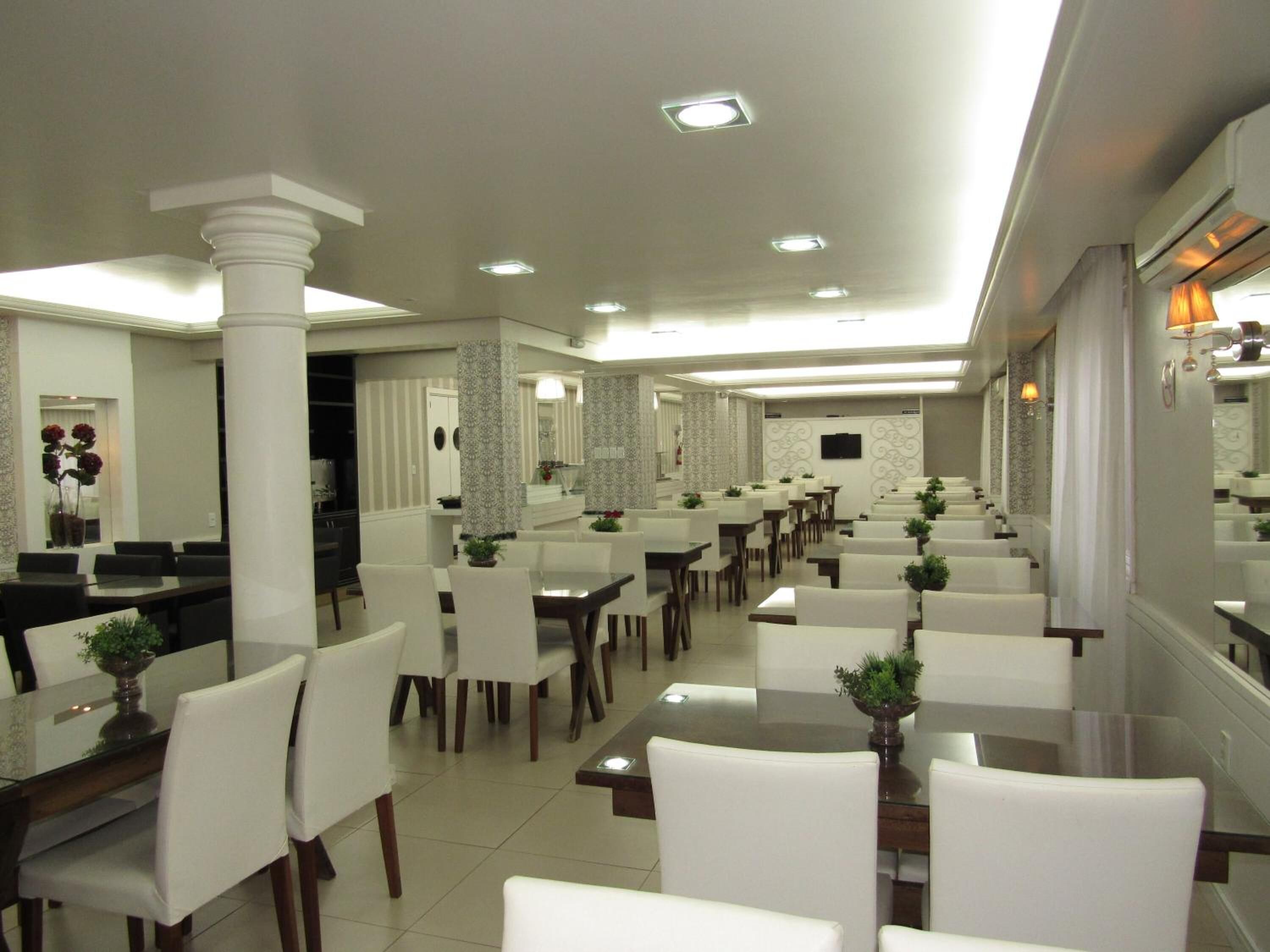 Un'ampia sala da pranzo con diversi tavoli e sedie, un pilastro centrale e un moderno design del soffitto.