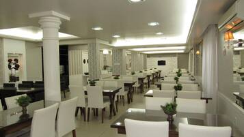 Un'ampia sala da pranzo con diversi tavoli e sedie, un pilastro centrale e un moderno design del soffitto.