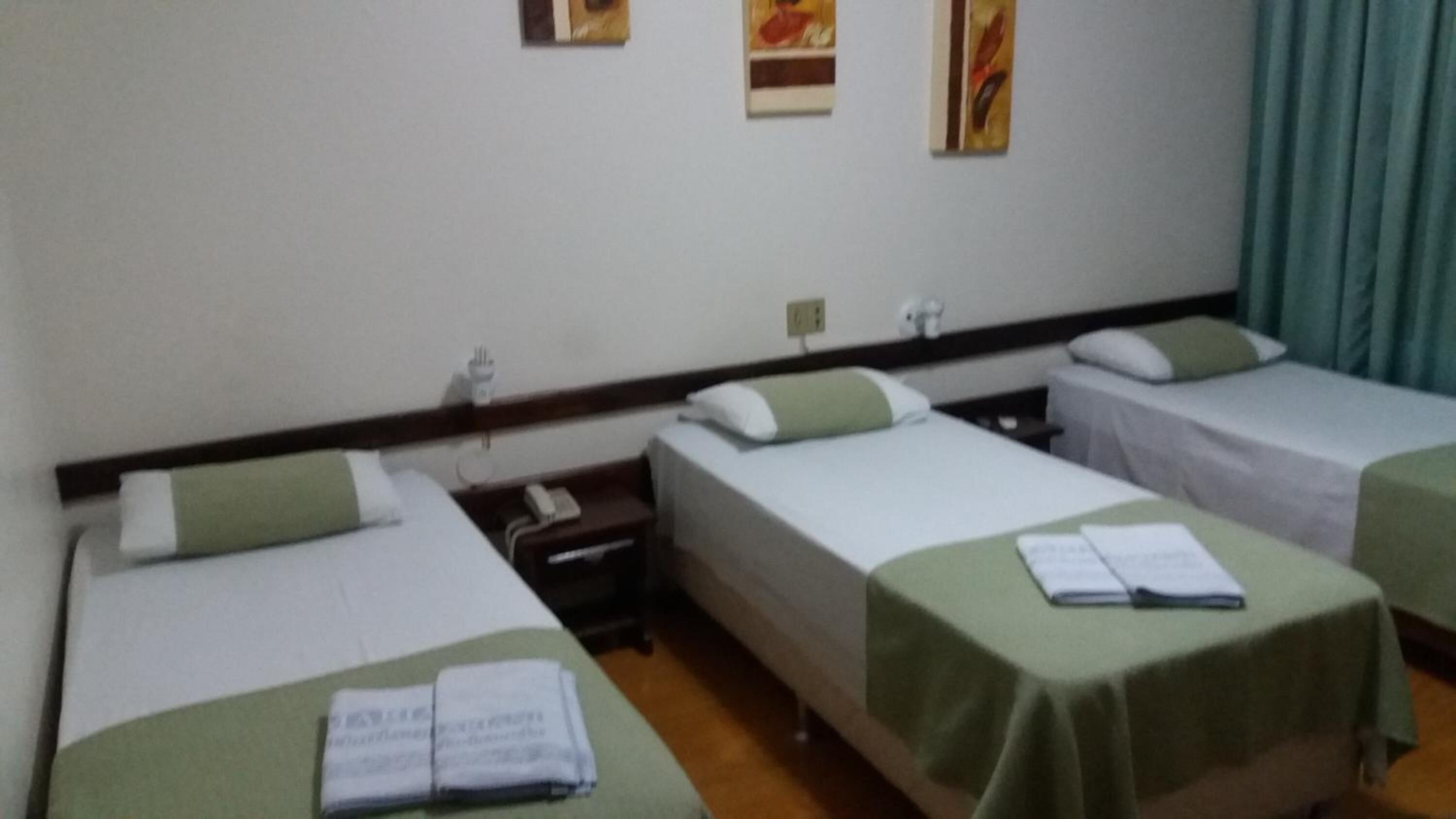 Une chambre d’hôtel avec deux lits simples, une table de chevet avec un téléphone et une petite table avec un livre et des papiers.