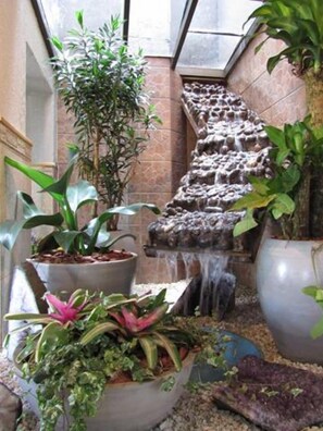 A stone staircase with water flowing down it, surrounded by potted plants. - Hotel Mariani (Lajeado)