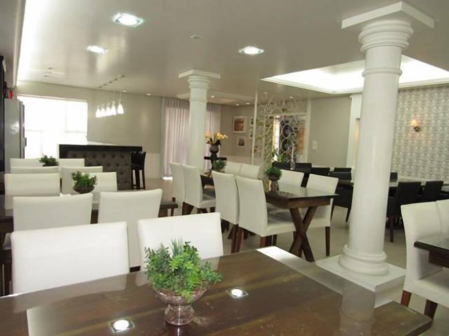 A dining area with white chairs, a wooden table, and a central plant.