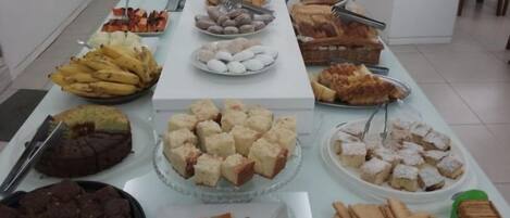 A buffet table with various food items including fruits, pastries, and desserts.