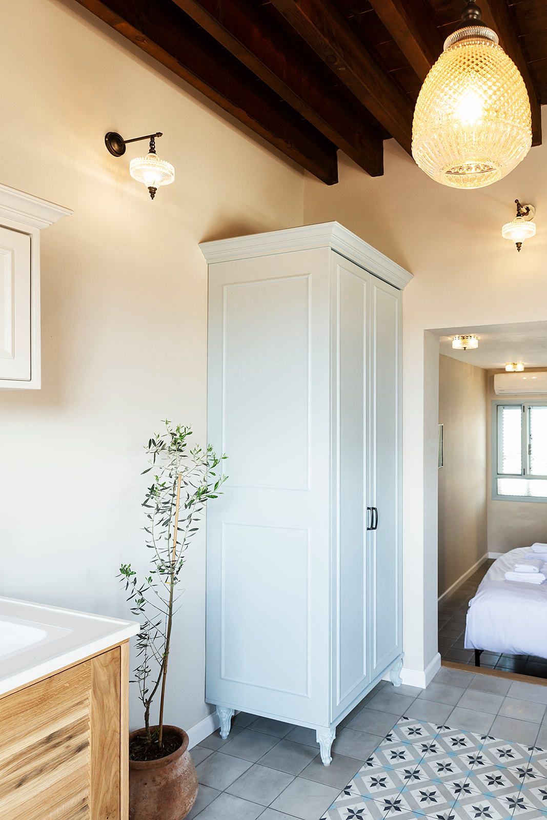 A room with a white wardrobe, a potted plant, and a patterned rug.