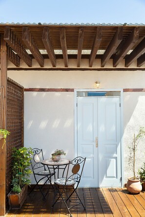 Una terraza de madera con una mesa, sillas y plantas en macetas.