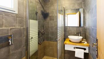 A modern bathroom with a glass-enclosed shower, a wooden vanity with a white sink, and a large mirror above the sink.