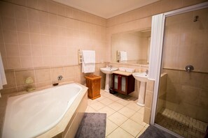 Bathroom features a large bathtub, two sinks, and a shower area with a glass door.