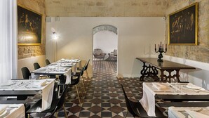 A dining area with tables set for service, a patterned floor, and paintings on the walls. - a.d. 1768 Boutique Hotel (Ragusa)
