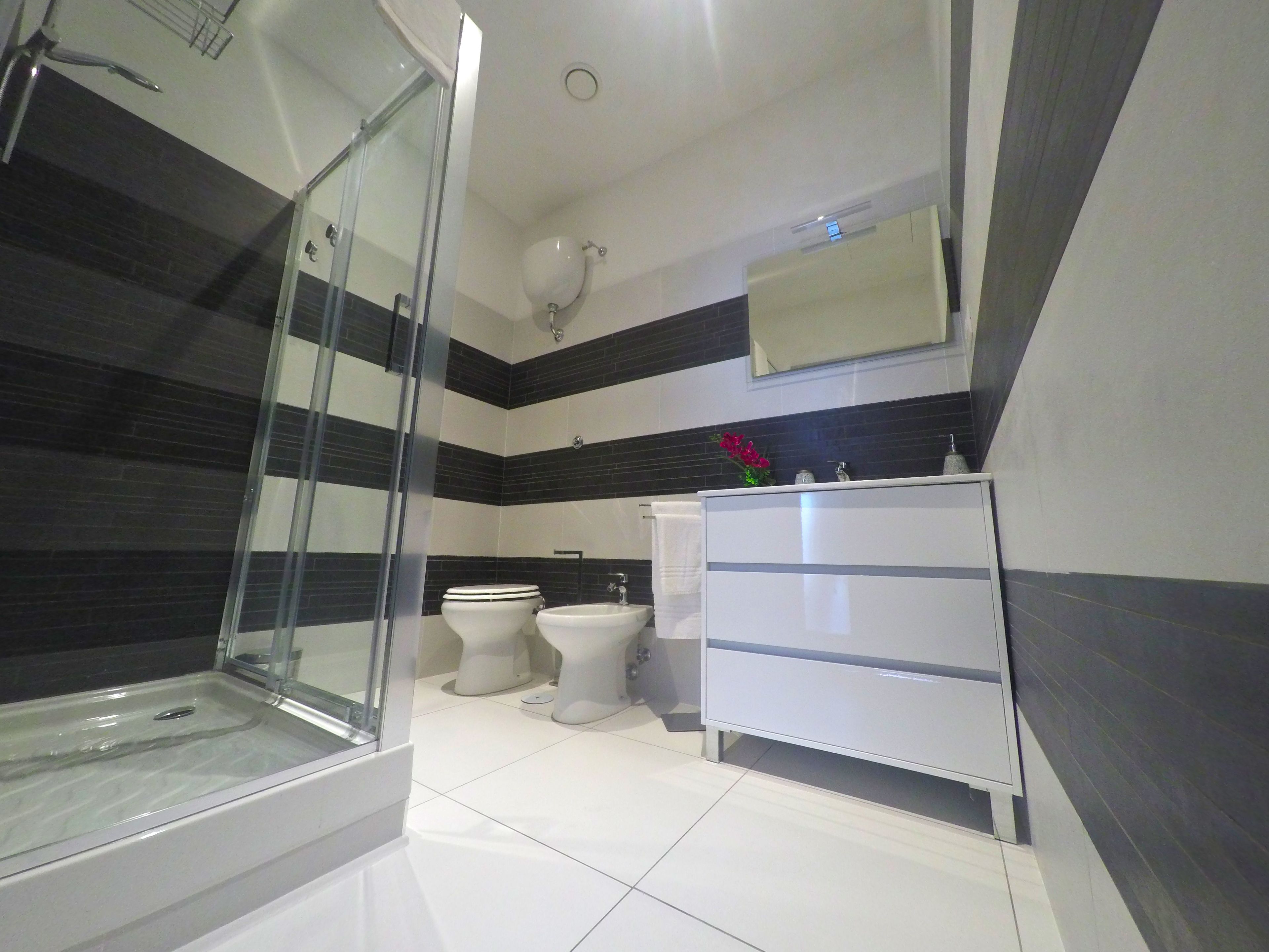 A modern bathroom with a glass shower enclosure, a white sink, and a vanity with drawers.