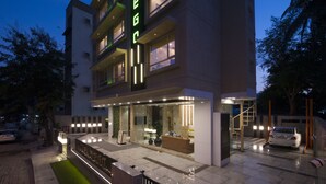 A modern hotel with a well-lit entrance, a visible reception desk, and a car parked outside. - Hotel Wego (Mumbai)