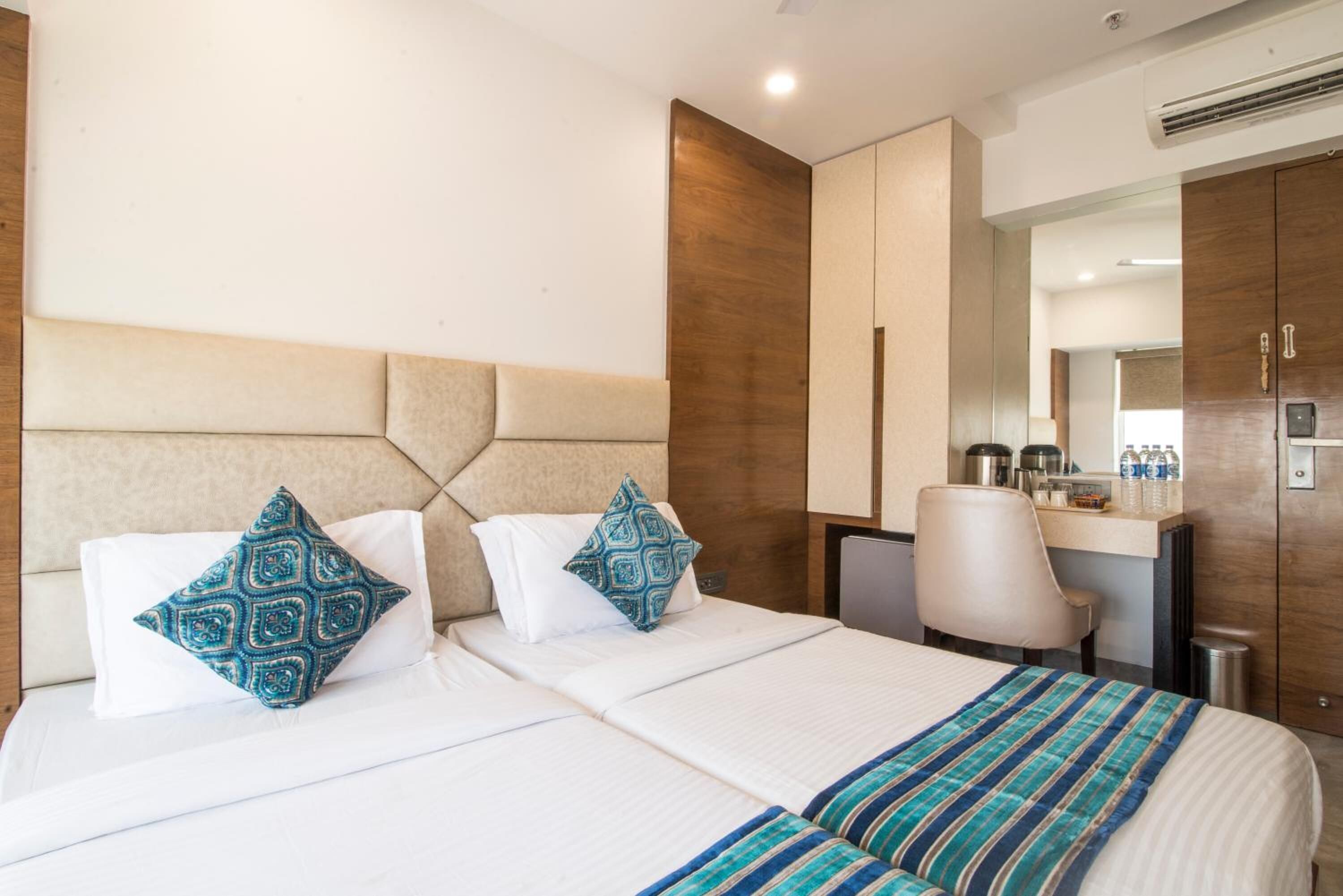 A hotel room with a large bed, two pillows, a desk, and a chair.