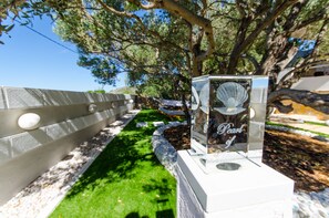 Stroll along the serene pathway lined with a low wall and shaded by a large tree.