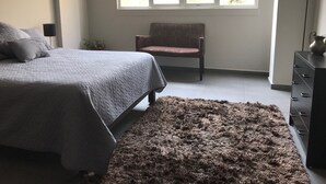 Una camera da letto con un letto, una sedia, un comò e una finestra vista alberi.