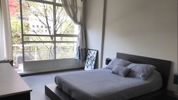 Una camera da letto moderna con un letto, comodini e una finestra con tende.