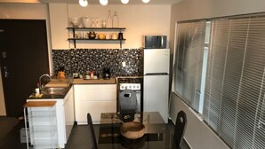 Una cucina compatta con un tavolo da pranzo, un fornello e un frigorifero.