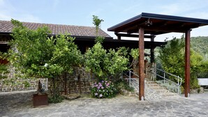 A stone building with a tiled roof, a wooden pergola, and a stone staircase leading to a covered area. - Il Vecchio Frantoio (Stella Cilento)