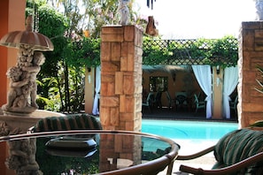 A poolside area with stone pillars, a glass table, and a statue. - Stephward Estate Country House (Margate)
