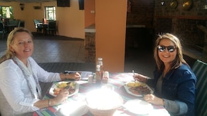Two people dining at an outdoor table with plates of food, a bottle, and condiments. - Stephward Estate Country House (Margate)