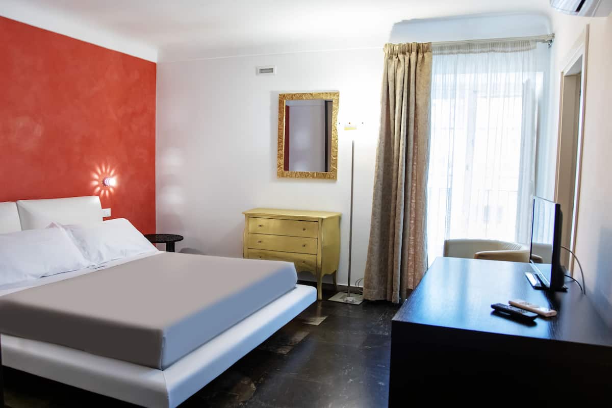 Una habitación de hotel con cama, escritorio, silla, cómoda y espejo.