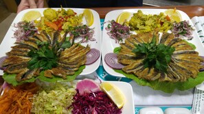 Two plates of food with fried fish, salad, and vegetables. - YZE Pirlanta Hotel (Malatya)