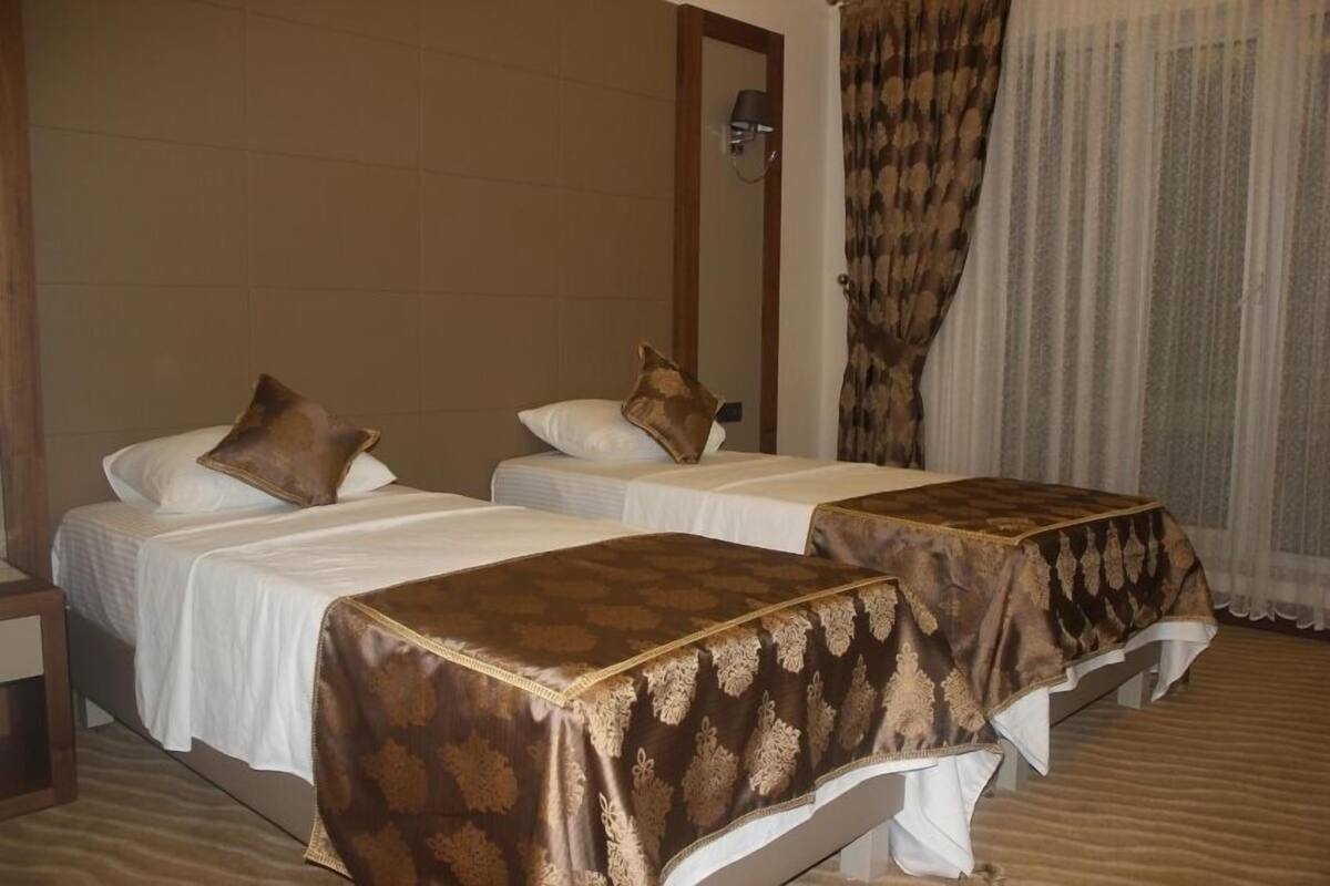 Une chambre d’hôtel avec deux lits simples, chacun recouvert d’une couverture marron et doté d’oreillers blancs.
