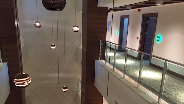 A modern interior with hanging pendant lights, a glass railing, and a corridor with doors. - YZE Pirlanta Hotel (Malatya)