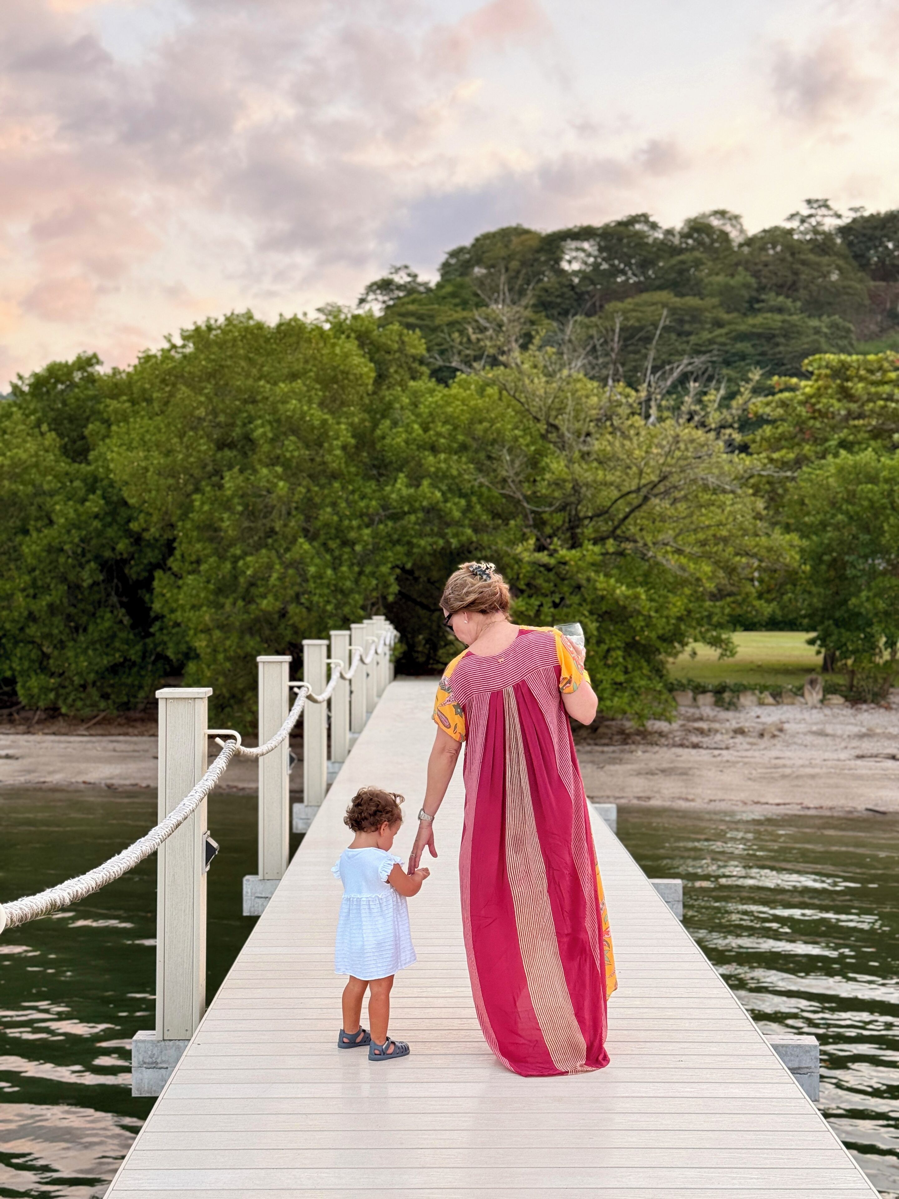 A wooden pier extending over water, with a woman and a child holding hands.