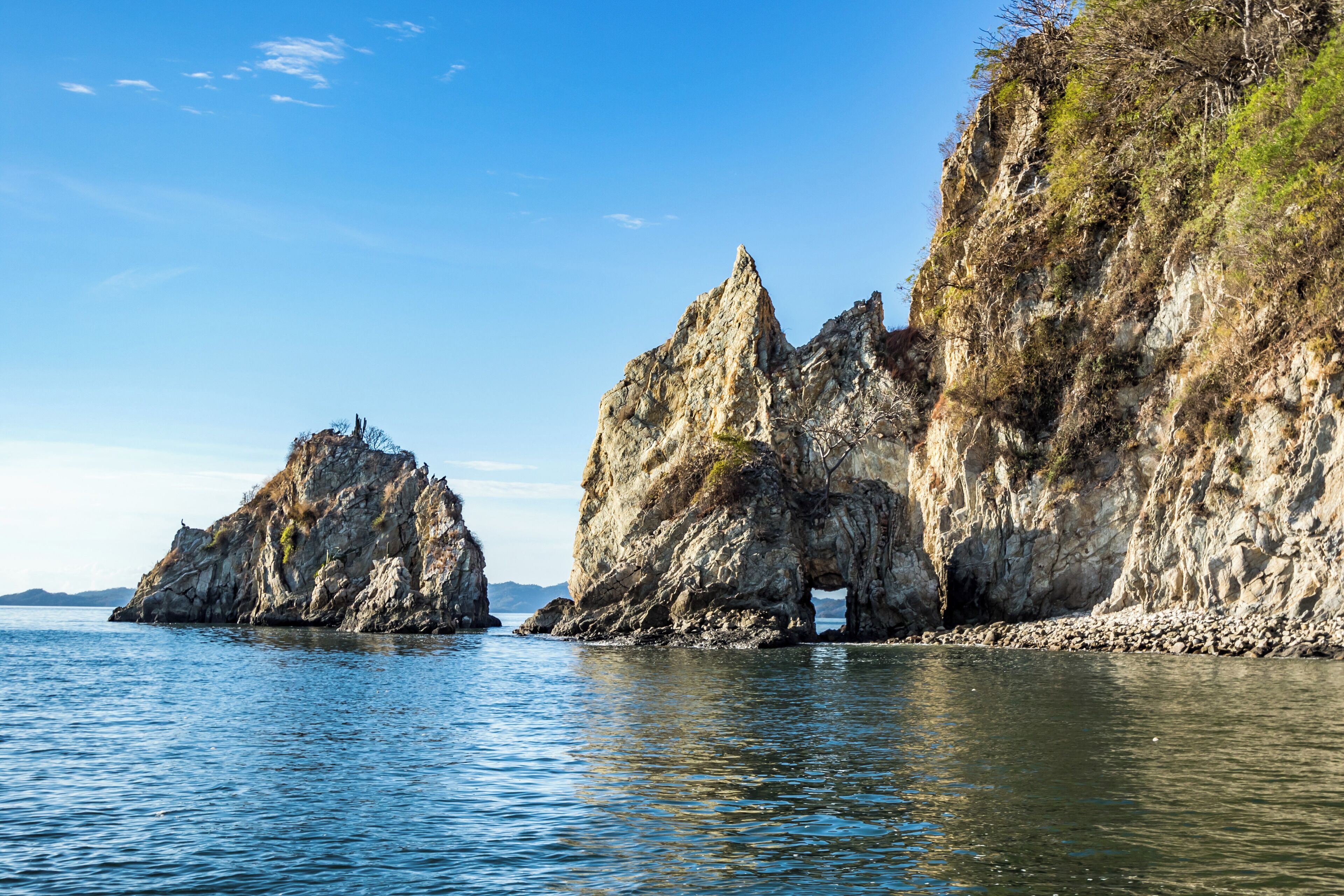 A coastal landscape with rocky cliffs and calm water.
