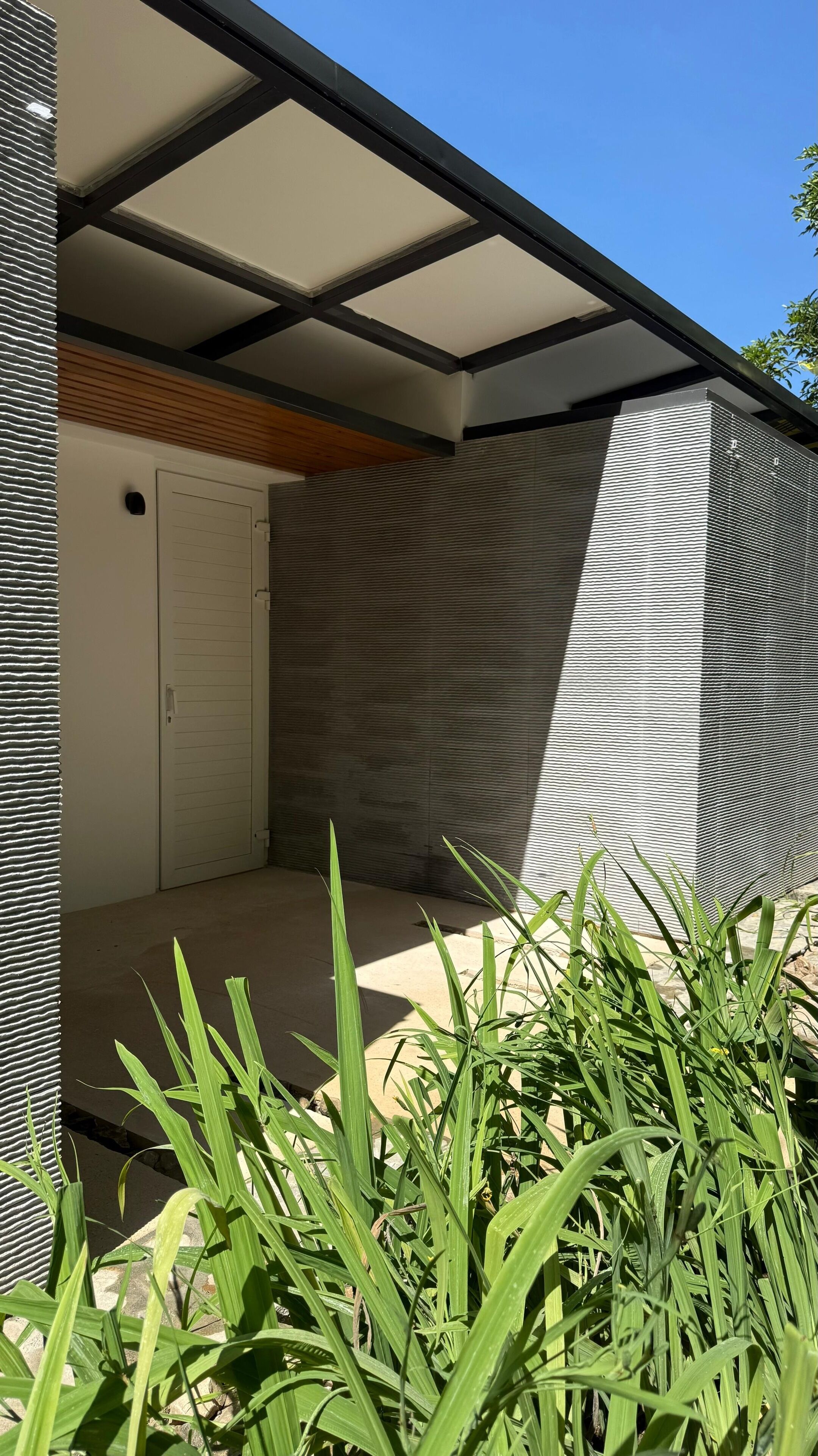 A modern building with a sloped roof, a wooden door, and a textured wall.