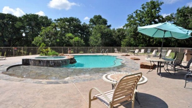 Piscina con hidromasaje, rodeada de sillones de descanso y una sombrilla.
