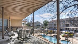 Un espacio al aire libre cubierto con piscina, sillas y mesas.