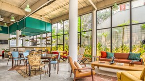 Un interior espacioso y luminoso con un amplio comedor, asientos cómodos y ventanas grandes que ofrecen vistas a la vegetación.
