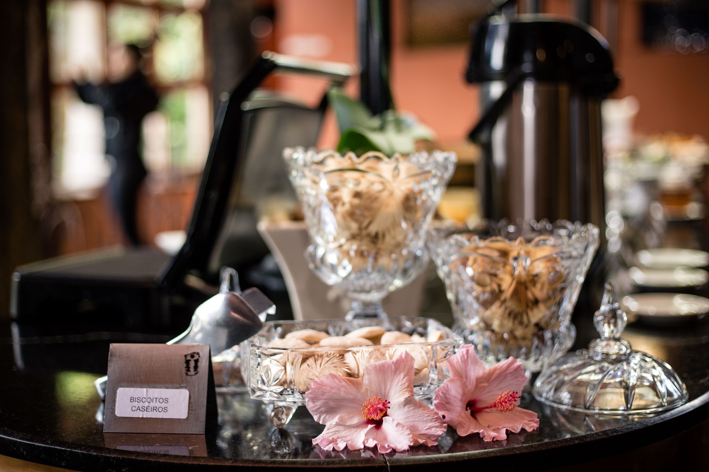 A tray with cookies, a coffee maker, and a glass bowl with flowers.