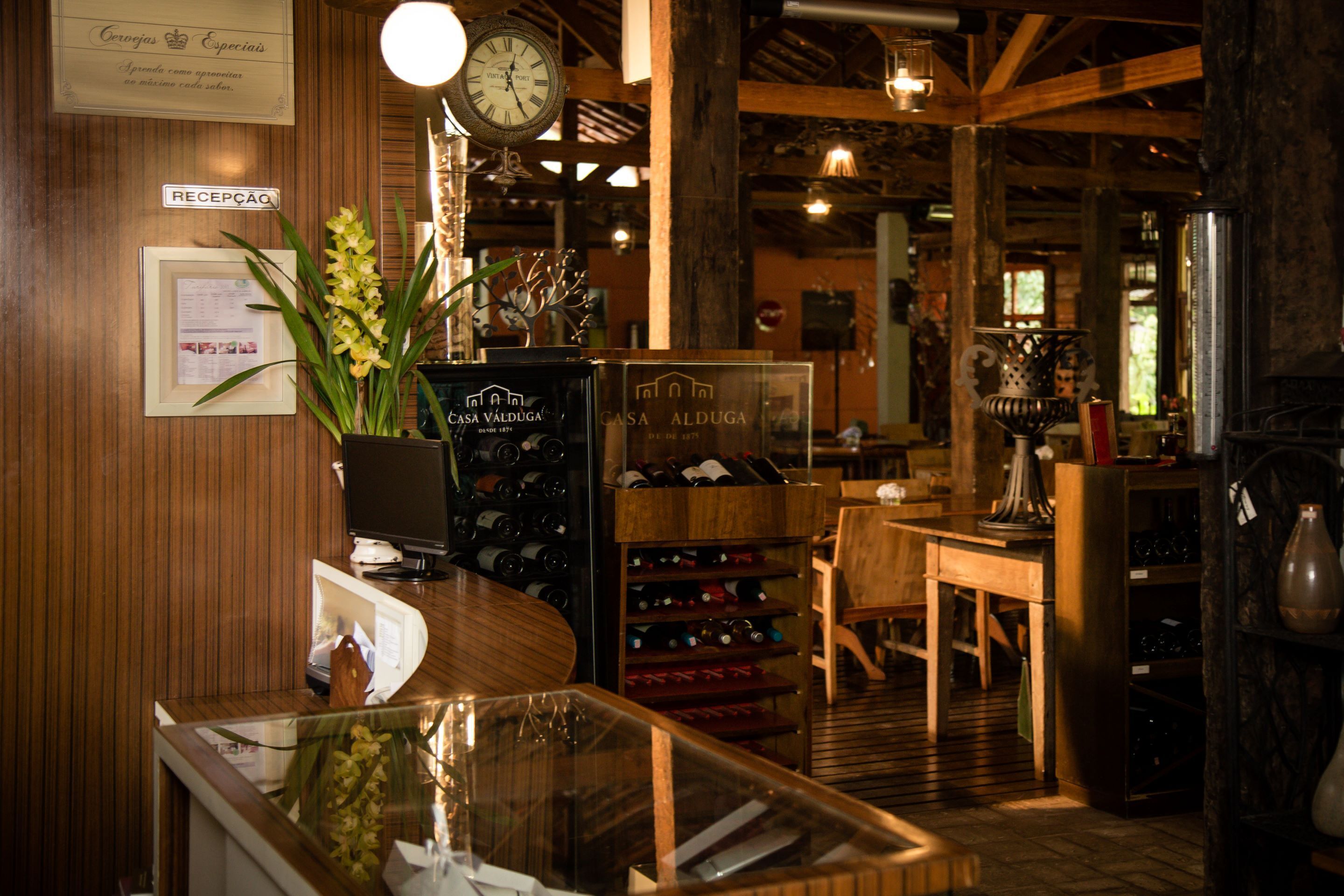 A reception area with a wooden interior, a clock, a reception desk, and a wine rack.