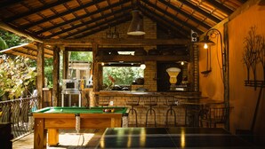 Un espace de loisirs intérieur accueillant, équipé d’une table de billard, d  ’une table de ping-pong et d’un bar avec des sièges.