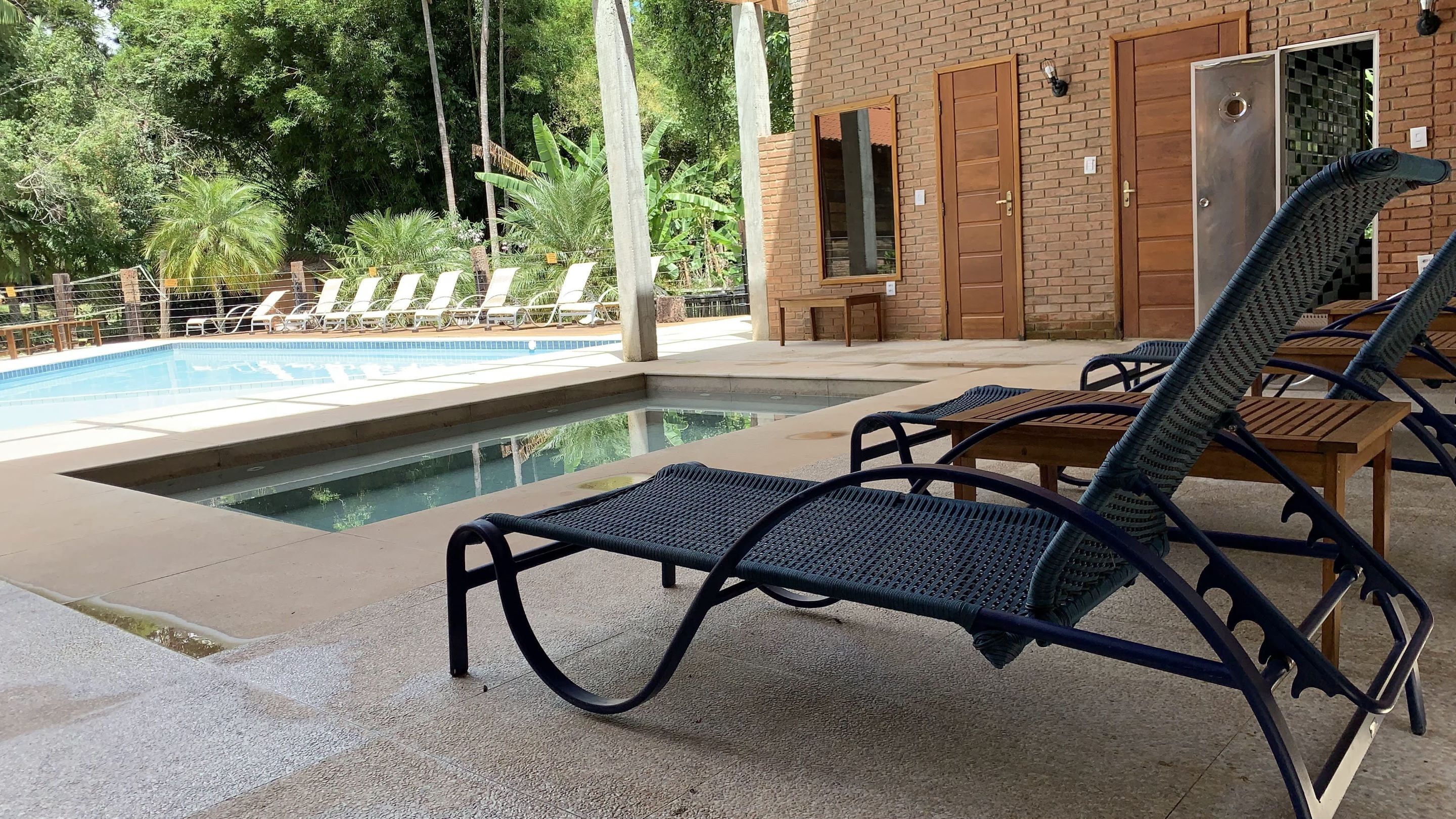 A poolside area with lounge chairs, a brick building, and a pool.