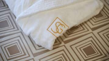A white towel with a gold embroidered logo on a patterned floor.