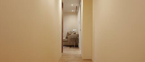 A narrow hallway with wooden flooring and beige walls.