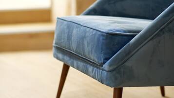 A blue armchair with wooden legs on a wooden floor.