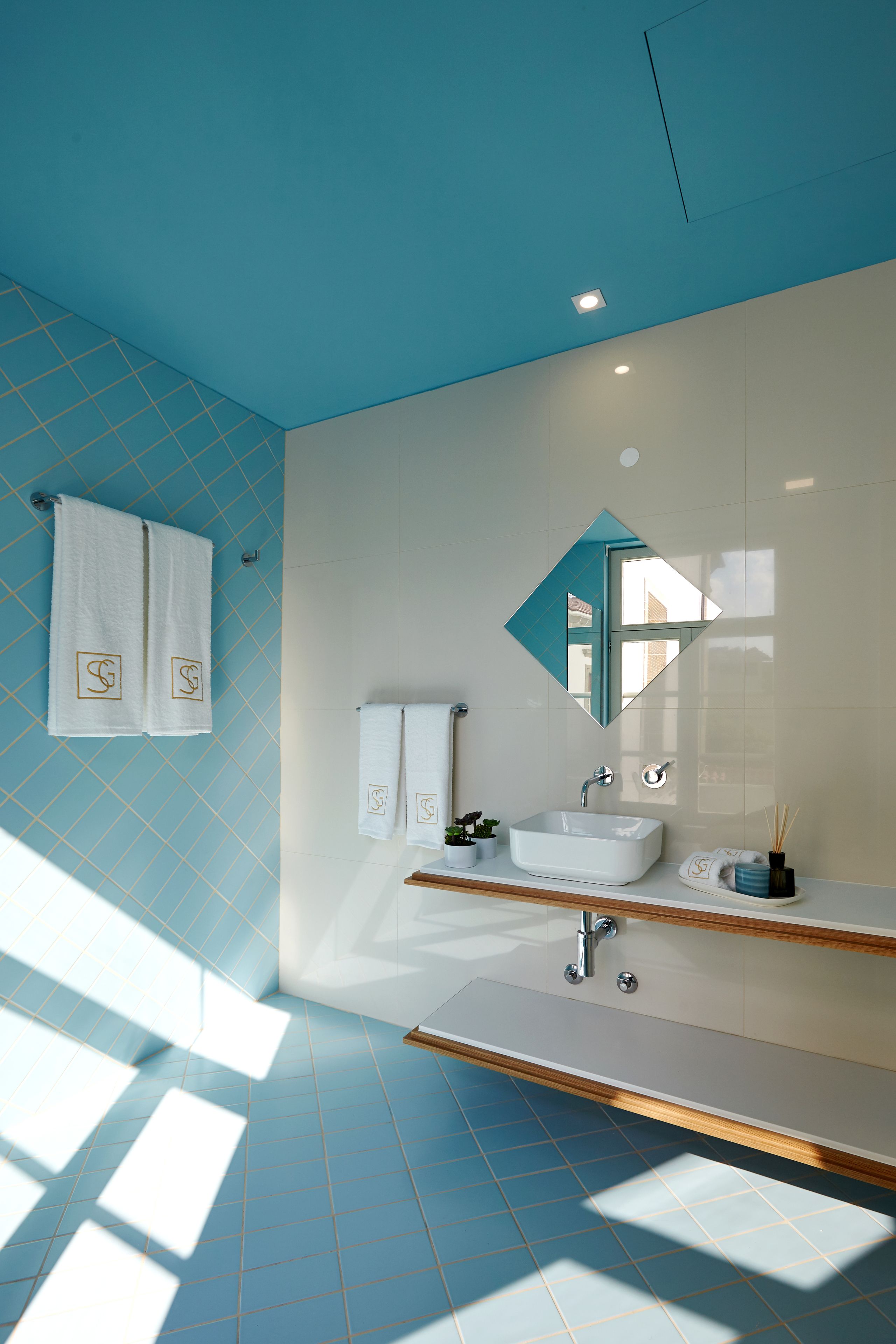 A bathroom with a blue tiled floor, a white sink, and a mirror with a geometric frame.