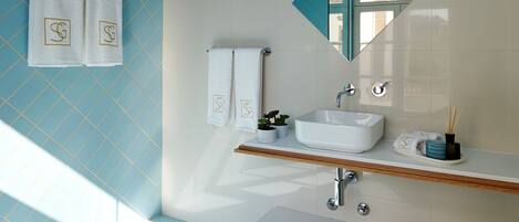 A bathroom with a blue tiled floor, a white sink, and a mirror with a geometric frame.